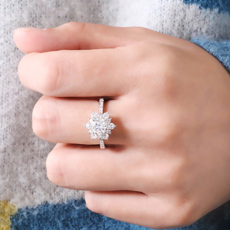 May include: A silver ring with a large, round, clear stone surrounded by smaller clear stones in a snowflake design.
