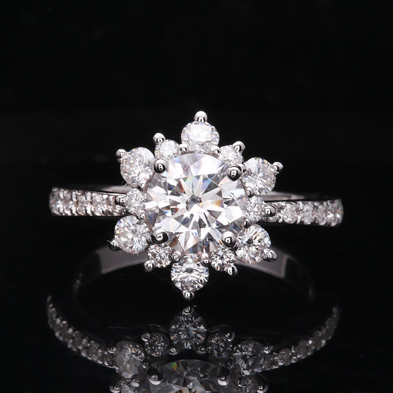 May include: A silver ring with a large, round, clear center stone surrounded by smaller, clear stones in a snowflake design.