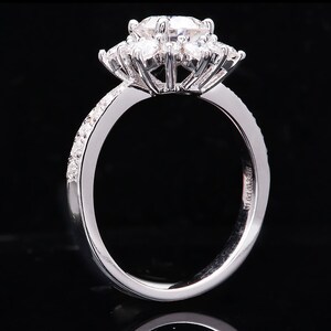 May include: A silver ring with a large, round, center diamond surrounded by smaller diamonds. The band is set with smaller diamonds and has the inscription "51.0ct. 0.035ct." on the inside.