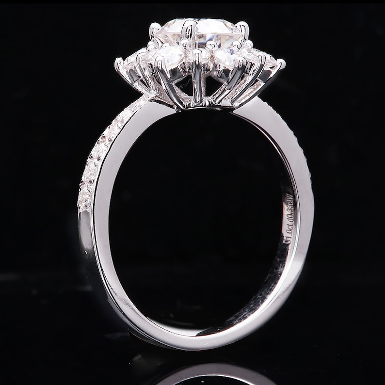 May include: A silver ring with a large, round, center diamond surrounded by smaller diamonds. The band is set with smaller diamonds and has the inscription "51.0ct. 0.035ct." on the inside.