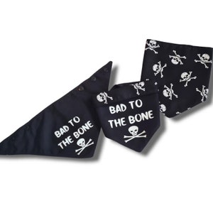 May include: Three black dog bandanas with white skull and crossbones designs. One bandana says "Bad to the Bone" and another says "Bad to the Bone" with a skull and crossbones.