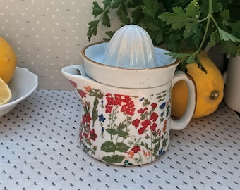 Exprimidor de limones antiguo, decorado con muchas flores silvestres de colores.