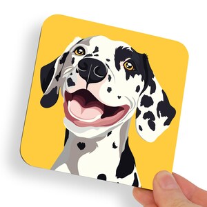 Peut inclure: Sous-verre carré avec une illustration de chien dalmatien souriant. Le chien a des taches noires, des oreilles noires et une langue rose, sur fond jaune. Le dessous de verre est tenu par une main.