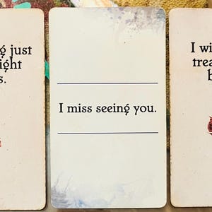 以下が含まれることがあります： オフホワイトの背景を持つ3枚の長方形のカード。左のカードには乾燥したバラと「The timing just wasn't right for us」という文字。中央のカードには空欄の線と「I miss seeing you」という文字。右のカードには乾燥したバラと「I wish I had treated you better」という文字が記されています。