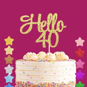 Pode incluir: Um bolo branco com granulado colorido e cobertura branca, coberto com um topo de bolo de glitter dourado que diz "Hello 40".