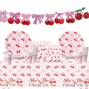 May include: A pink party set with a cherry theme. Includes plates, cups, napkins, and a tablecloth with the text "She's The Cherry On Top". A banner with cherries and bows hangs above.