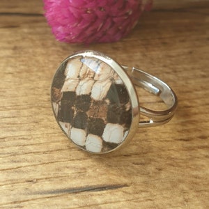 Op de afbeelding: Een zilveren ring met een ronde, heldere glazen setting met een zwart-wit patroon.