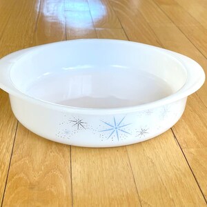 May include: White ceramic baking dish with a blue and white starburst pattern. The dish is oval shaped and has a rim.