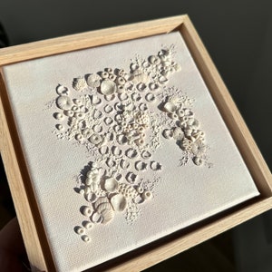 May include: A framed canvas with a white background and a 3D design of white coral shapes.