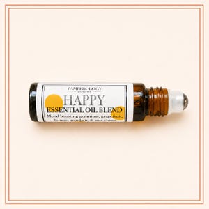 K&ouml;nnte beinhalten: Eine kleine Braunglas-Roll-on-Flasche mit einer &auml;therischen &Ouml;lmischung. Das wei&szlig;e Etikett tr&auml;gt den Text PAMPEROLOGY LONDON, HAPPY ESSENTIAL OIL BLEND und listet Geranie, Grapefruit, Zitrone, Mandarine und May Chang als Inhaltsstoffe auf.