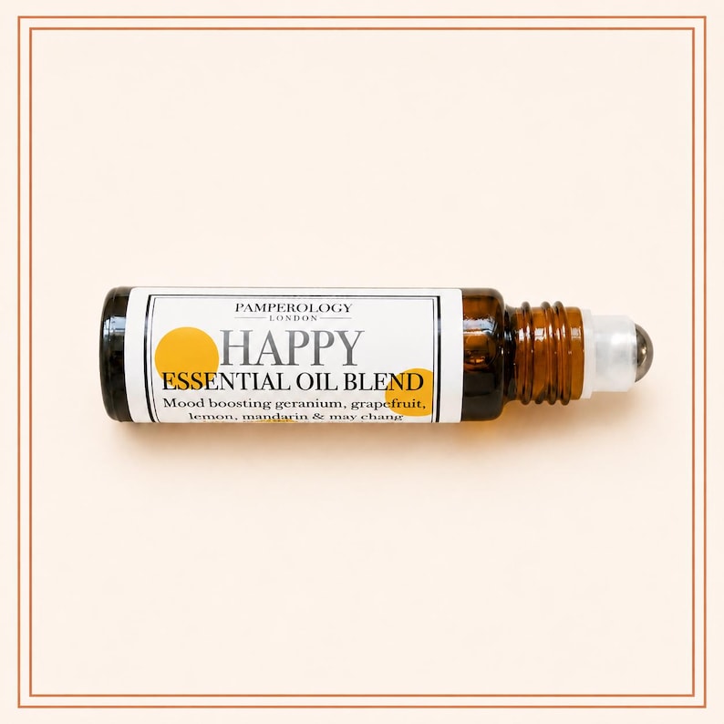 K&ouml;nnte beinhalten: Eine kleine Braunglas-Roll-on-Flasche mit einer &auml;therischen &Ouml;lmischung. Das wei&szlig;e Etikett tr&auml;gt den Text PAMPEROLOGY LONDON, HAPPY ESSENTIAL OIL BLEND und listet Geranie, Grapefruit, Zitrone, Mandarine und May Chang als Inhaltsstoffe auf.