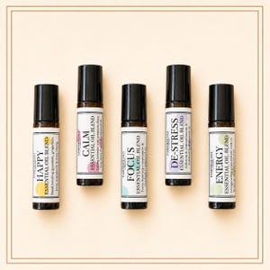 May include: Five amber glass roller bottles with black caps, each featuring a white label with the Pamperology London logo. The labels are titled Happy, Calm, Focus, De-Stress, and Energy, each with a unique coloured circle and ingredient text.