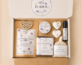 Könnte beinhalten: Eine weiße Geschenkbox mit der Aufschrift SPA IN A BOX enthält einen braunen Beutel mit Lavendelbadesalz mit einem Holzherz, eine runde Dose mit Balsam, zwei herzförmige Seifen, eine kleine Flasche ätherisches Öl und einen Lavendel-Badeteebeutel.