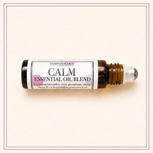 K&ouml;nnte beinhalten: Eine kleine Roll-on-Flasche aus bernsteinfarbenem Glas mit einer &auml;therischen &Ouml;lmischung. Das wei&szlig;e Etikett tr&auml;gt den Text PAMPEROLOGY LONDON, CALM ESSENTIAL OIL BLEND und listet Lavendel, Rosengeranie, Ylang-Ylang und Zedernholz in Traubenkern&ouml;l auf.