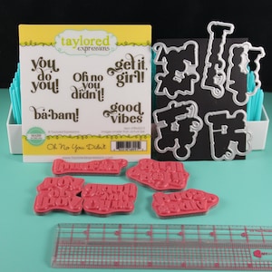 Puede incluir: Un juego de manualidades con sellos y troqueles metálicos. Incluye frases como «You do you!» y «Good Vibes». Se incluye una regla para medir. El embalaje lleva la inscripción «Oh No You Didn't».