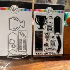 Puede incluir: Dos juegos de manualidades. Uno incluye troqueles metálicos para un trofeo, una pancarta y estrellas. El otro juego presenta sellos transparentes con frases como "Best of the Best" para hacer tarjetas.