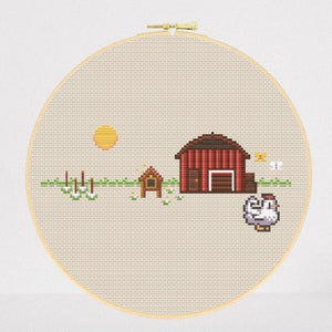 Peut inclure: Un cerceau de broderie au point de croix représentant une grange rouge, un petit poulailler jaune, une poule blanche et un soleil jaune. La scène se déroule dans un champ vert avec des fleurs blanches.