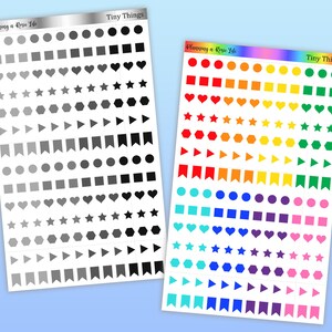 May include: Two sticker sheets with various shapes in grayscale and rainbow colors. The grayscale sheet has circles, squares, hearts, stars, hexagons, triangles, and banners. The rainbow sheet has the same shapes in a gradient of colors. Both sheets have the text "Tiny Things" and "Planning a Rosie Life".