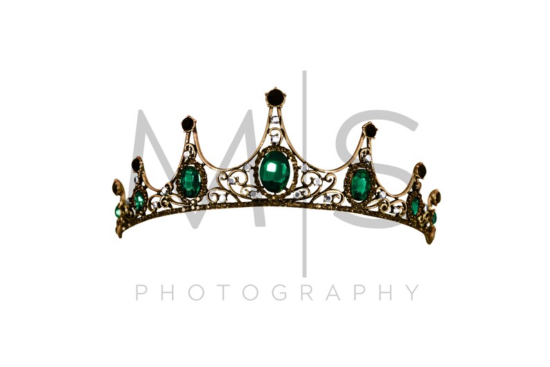 May include: A gold crown with green gemstones and clear rhinestones. The crown has a delicate, ornate design.