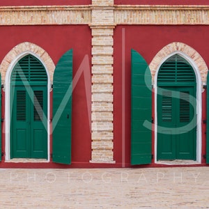May include: Two green wooden doors with shutters are open on a red brick building with a yellow brick trim. The doors are arched and have a white trim around the arch.