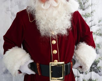 May include: A Santa Claus wearing a red velvet suit with gold trim, a white fur-trimmed hat, and a white beard and moustache. He is wearing a black belt with a gold buckle.