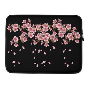 Op de afbeelding: Zwarte laptophoes met een roze kersenbloesem ontwerp. De bloemen vallen van een tak en zijn verspreid over een zwarte achtergrond.