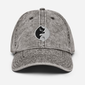 May include: A grey vintage-style baseball cap with a black and white yin yang symbol featuring a cat silhouette.