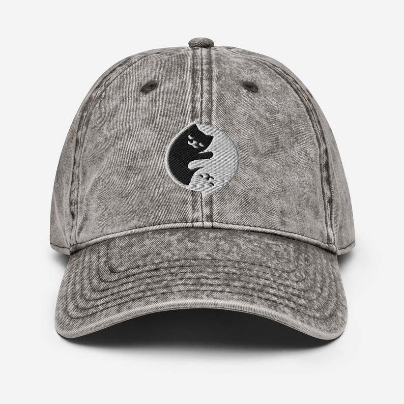May include: A grey vintage-style baseball cap with a black and white yin yang symbol featuring a cat silhouette.