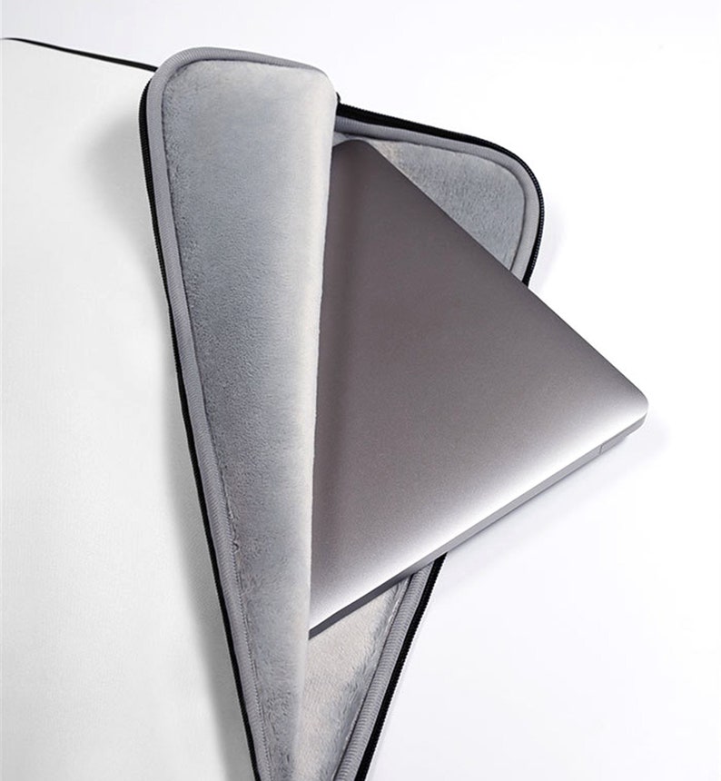 May include: A gray laptop computer partially inserted into a gray, plush-lined laptop sleeve. The sleeve has a black zipper and trim, and is set against a white background. The laptop is silver.