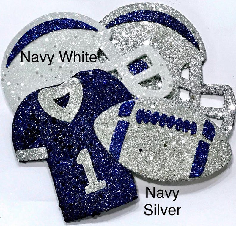 Pu&ograve; includere: Decorazioni glitterate a tema football, blu navy e argento. Include un casco da football, un pallone da football e una maglia con il numero 1. Il testo "Navy White" e "Navy Silver" &egrave; visibile.