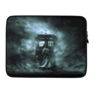 May include: Black laptop sleeve featuring a scene with a blue police box and a person in a long coat. The police box has the words "POLICE BOX" on top. The background is a dark, misty scene.
