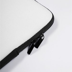 May include: Close-up of a white laptop sleeve with a black zipper and pull tabs.