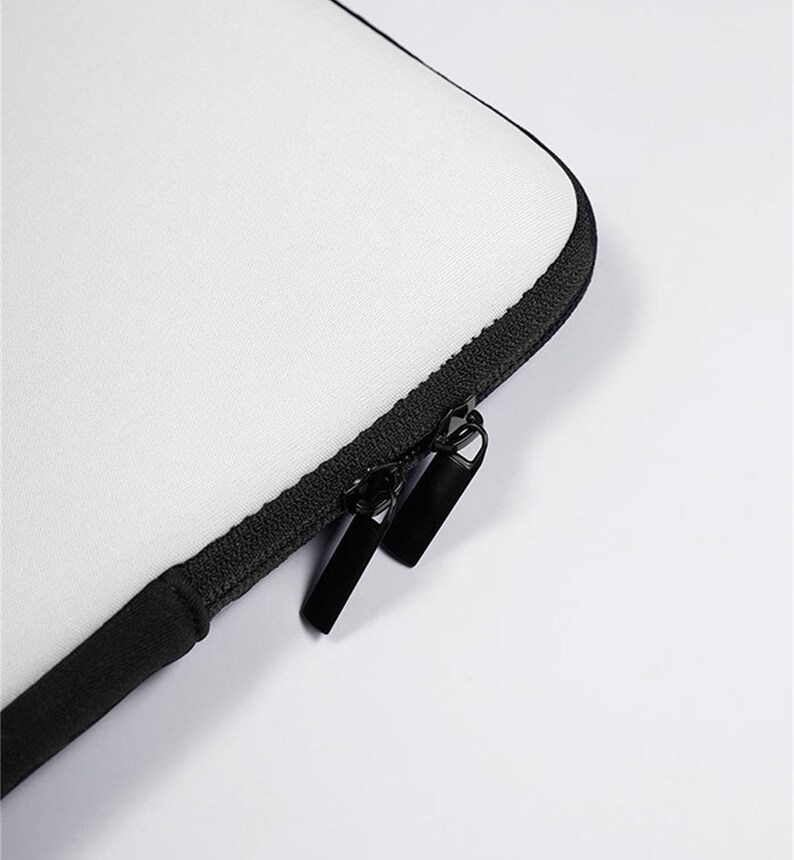 May include: Close-up of a white laptop sleeve with a black zipper and pull tabs.