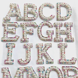 May include: A set of 14 white felt letters decorated with colorful pearls and rhinestones. The letters are A, B, C, D, E, F, G, H, I, J, K, L, M, N, O, and P.