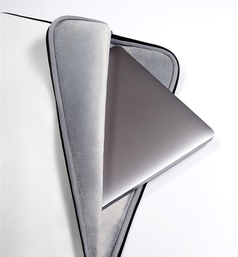 May include: A gray laptop sleeve with a black zipper and a soft gray lining. A silver laptop is partially inside the sleeve.