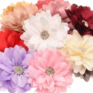 Könnte beinhalten: Sortiment aus zehn Stoffblumen-Haarklammern in verschiedenen Farben, darunter Rot, Weiß, Rosa, Lila und Creme. Jede Blume hat einen Strassstein in der Mitte.