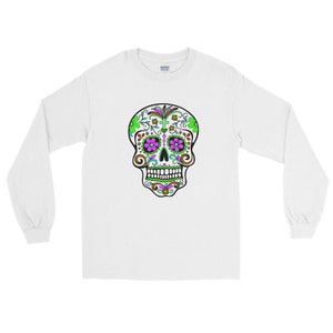 May include: White long-sleeve t-shirt with a colorful sugar skull design. The skull has green, pink, and brown details.