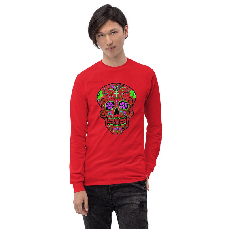 May include: Red long-sleeve shirt with a colorful sugar skull design. The skull has green, pink, and black details.