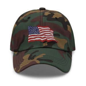 Peut inclure: Une casquette de baseball camouflage avec un drapeau américain brodé sur le devant.