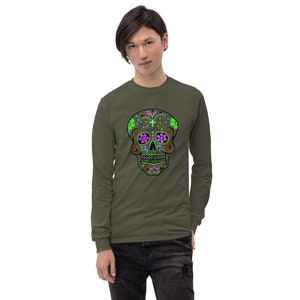 May include: A long-sleeved shirt in olive green with a colorful sugar skull design on the front. The skull is brown with pink and green floral details.