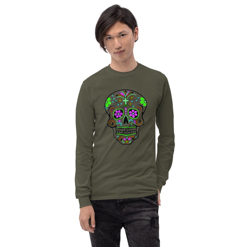 May include: A long-sleeved shirt in olive green with a colorful sugar skull design on the front. The skull is brown with pink and green floral details.