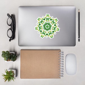 May include: A green and yellow mandala sticker with a floral design. The sticker is on a silver laptop computer.
