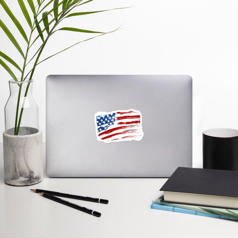 May include: A sticker featuring a distressed American flag design. The flag is red, white, and blue with a white background. The sticker is perfect for adding a patriotic touch to laptops, water bottles, or other surfaces.