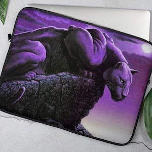 May include: Purple laptop sleeve with a black panther sitting on a rock against a purple and white sky.