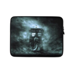 May include: Laptop sleeve featuring a dark, atmospheric design. The image depicts a person standing before a blue police box, surrounded by swirling mist. The police box has the words "POLICE BOX" on top.