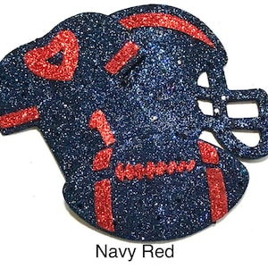 Pu&ograve; includere: Un design di maglia e casco da football blu navy glitterato con accenti rossi. La maglia presenta un cuore, il numero 1 e la parola "football". Il testo "Navy Red" &egrave; in basso.