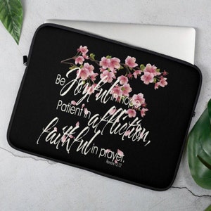 Puede incluir: Funda para portátil negra con un diseño floral rosa y el texto "Sed alegres en la esperanza, pacientes en la tribulación, constantes en la oración. Romanos 12:12"