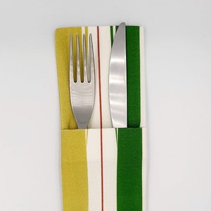 May include: A striped fabric napkin with a gold, white, and green pattern. A silver fork and knife are placed inside the napkin.