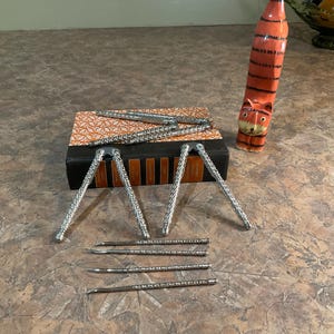 May include: A collection of nutcrackers and picks. The nutcrackers are silver-toned with a textured design. A decorative tiger-shaped bottle is also present. The items are arranged on a brown and orange patterned surface.