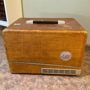 May include: A vintage brown and beige projector with a black handle and a silver grill on the front. The projector has a red and white circular label with the text "Kodak 800" on it.